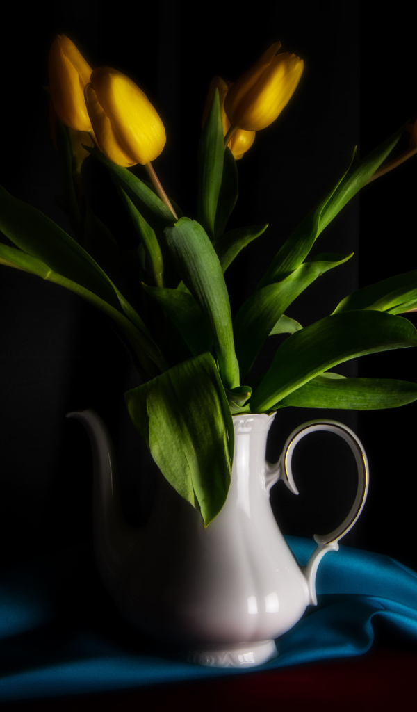 Желтые тюльпаны в белой вазе на черном фоне