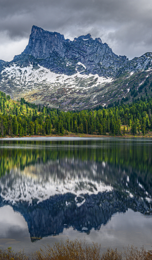 Красивая гора под грозовым небом отражается в озере 