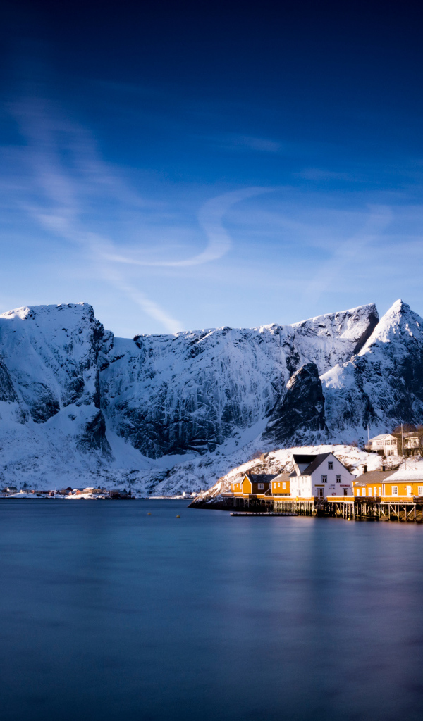 Красивый вид на дома у заснеженных гор под голубым небом 