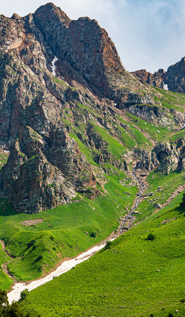 Большие каменные горы с зеленым ковром травы