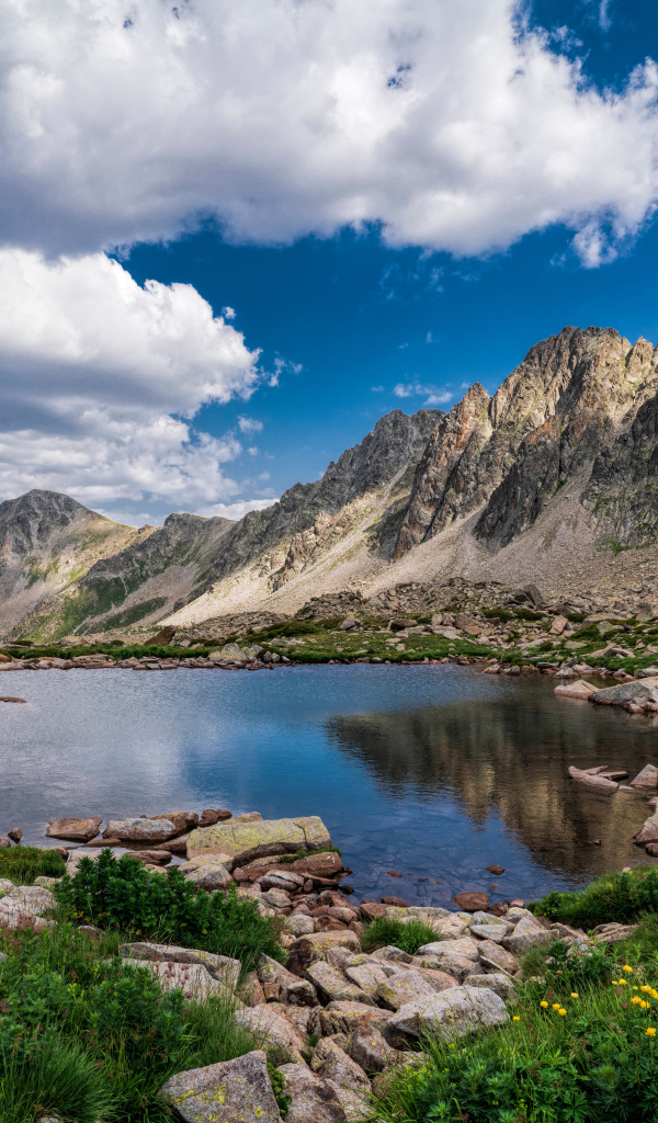 Горы под голубым небом с белыми облаками у озера, Андорра 