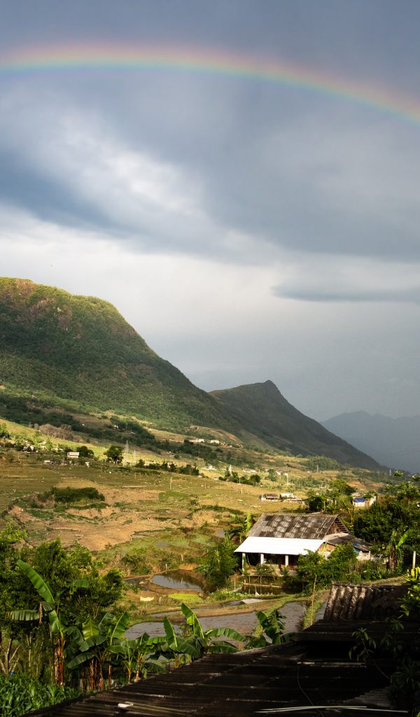 Большая разноцветная радуга в небе над горами