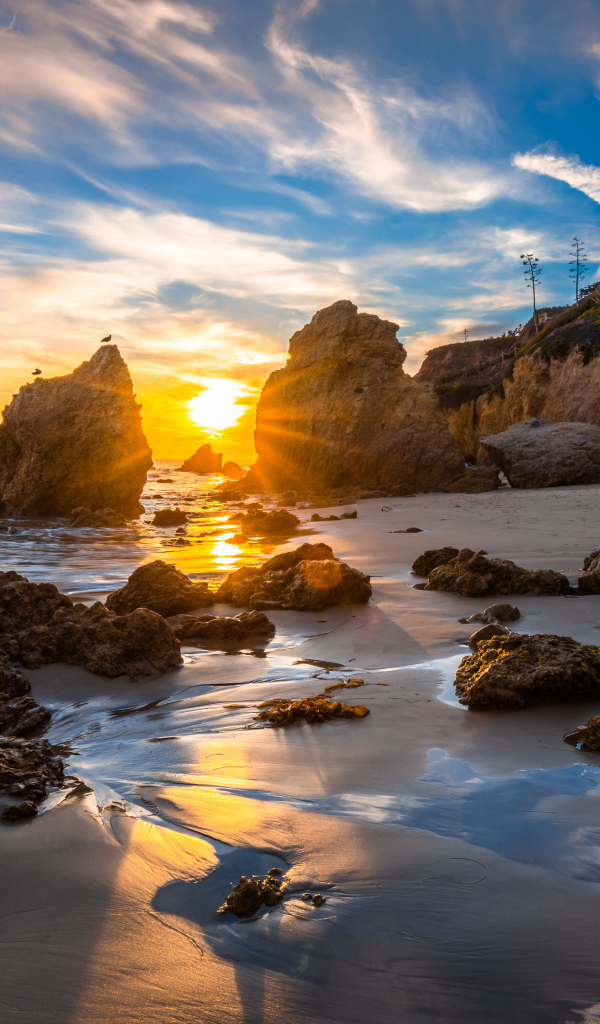 Яркий рассвет летнего солнца над скалами и океана