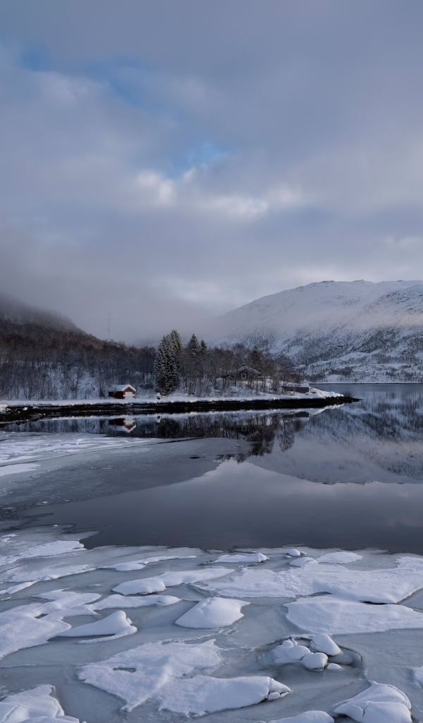 Покрытое льдом холодное озеро у гор в тумане