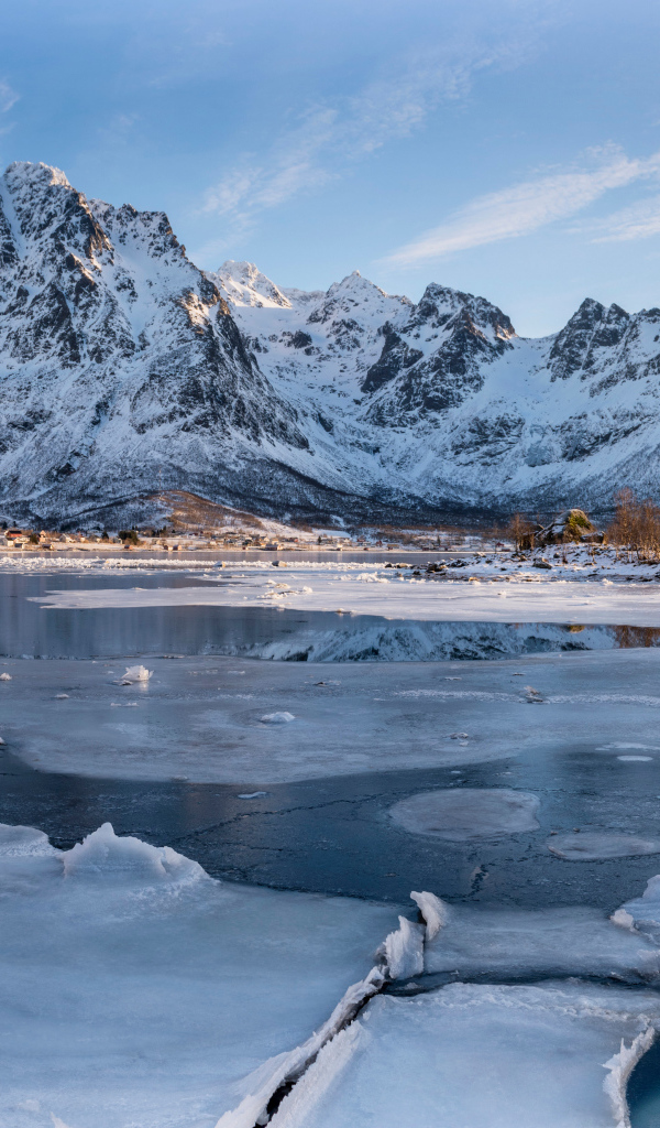 Покрытое льдом озеро у заснеженной горы