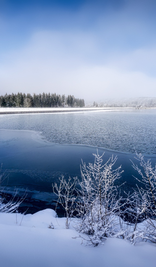 Покрытая льдом река  с заснеженными берегами зимой