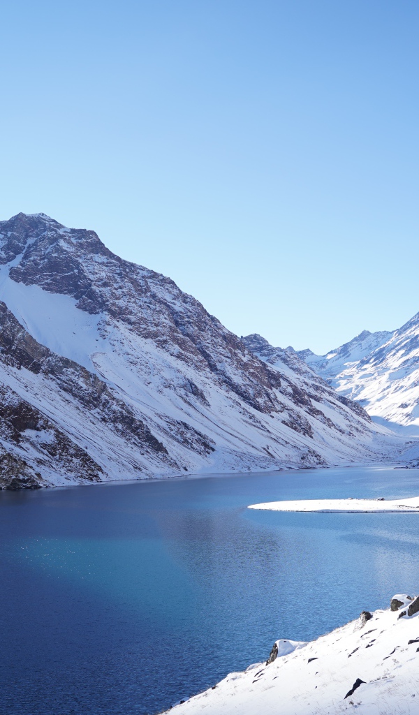 Озеро у покрытых снегом гор под голубым небом