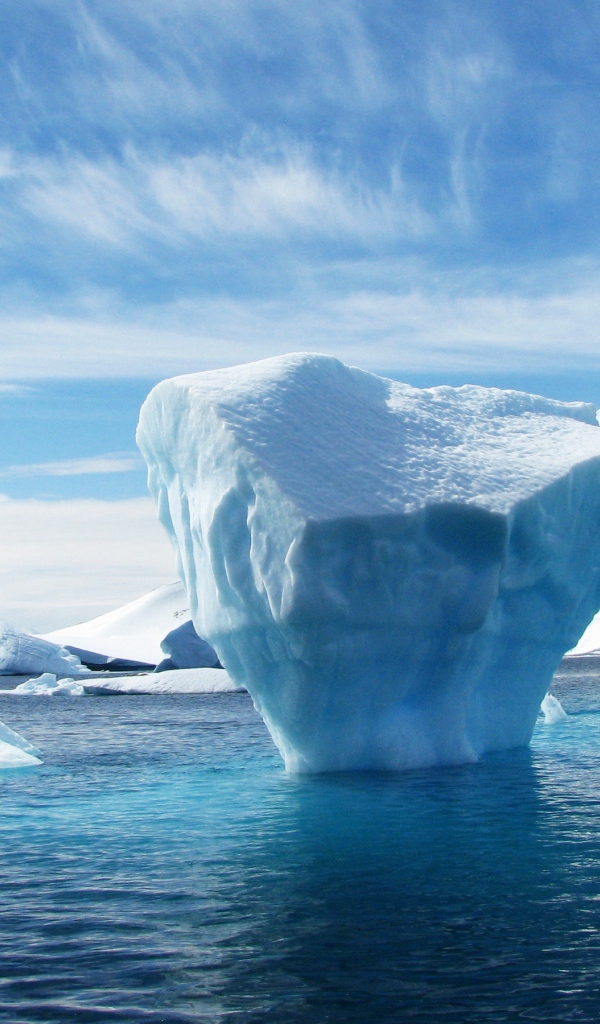 Большой голубой айсберг в воде у гор 