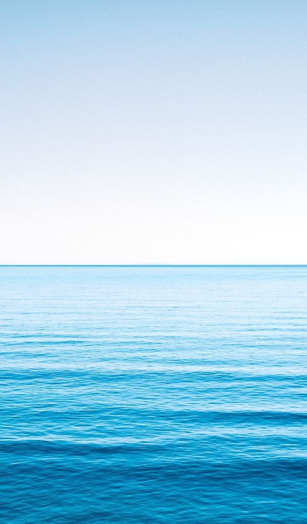 Спокойная голубая морская вода под голубым небом 