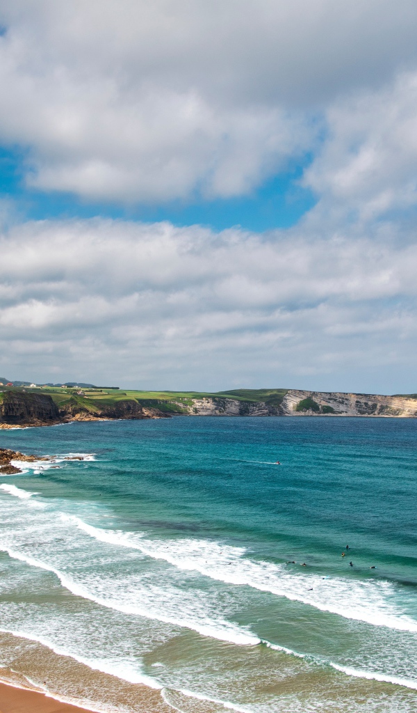 Спокойные волны на берегу залива под голубым небом с облаками