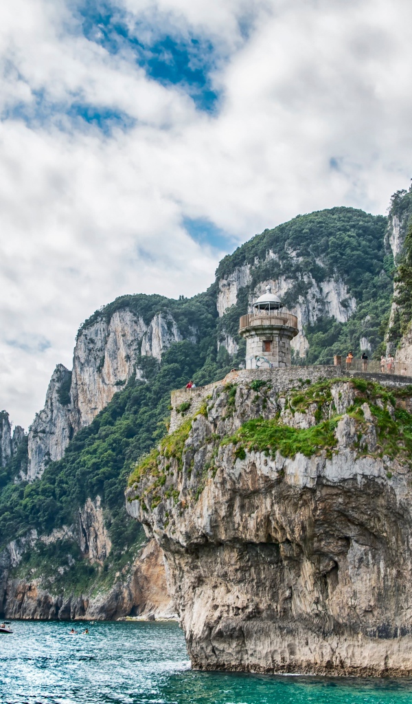 Высокие скалы у моря под белыми облаками 