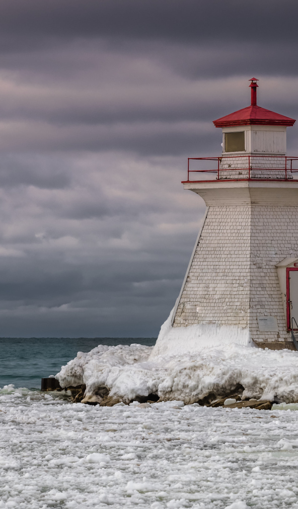 Маяк на покрытом льдом берегу у моря