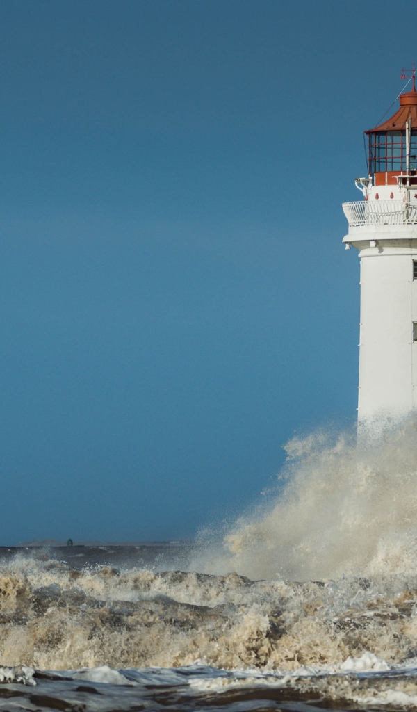 Бушующие белые волны бьются о маяк 