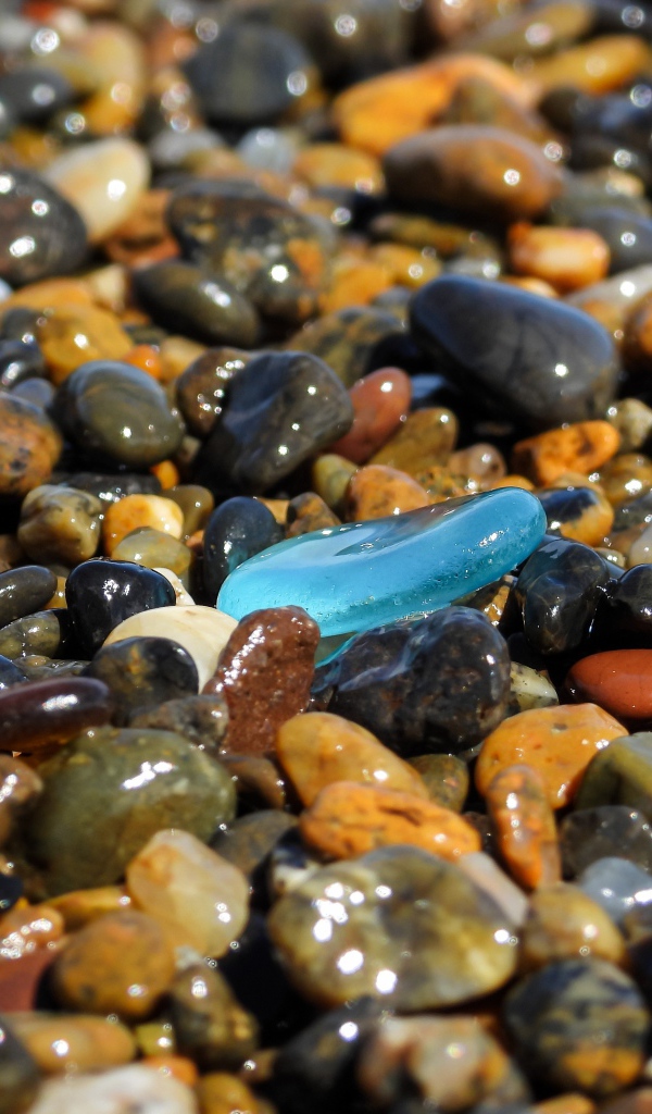 Гладкие разноцветные мелкие камни на пляже 