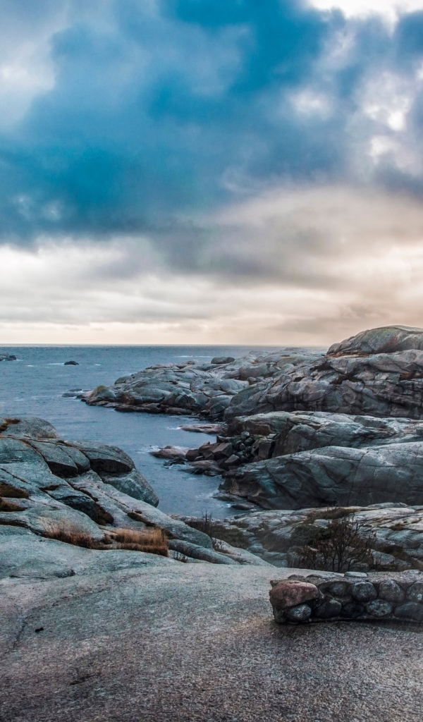 Каменный берег у тихого моря под черными облаками