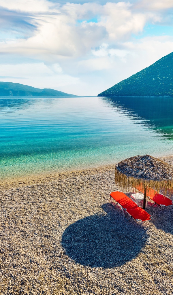 Шезлонги стоят на берегу озера у гор 