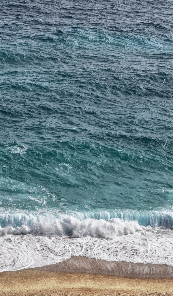 Белая пена от голубой морской воды на песке 