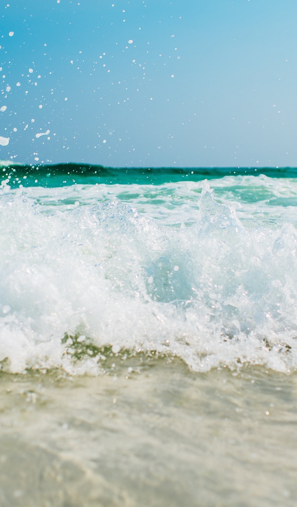 Белая морская пена бьется об берег 