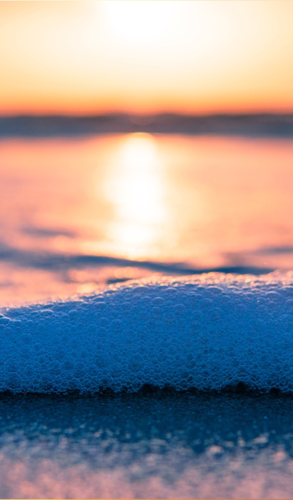 White sea foam with bubbles at sunset