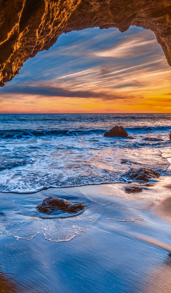 Закат солнца в каменной арке в море