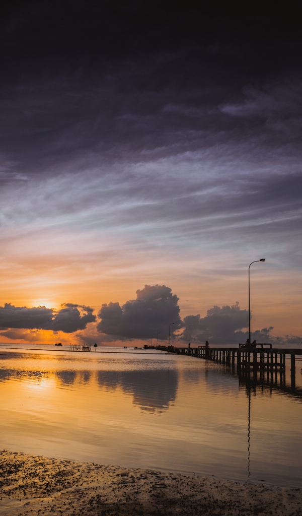 Деревянный мост на реке в лучах  солнца на закате