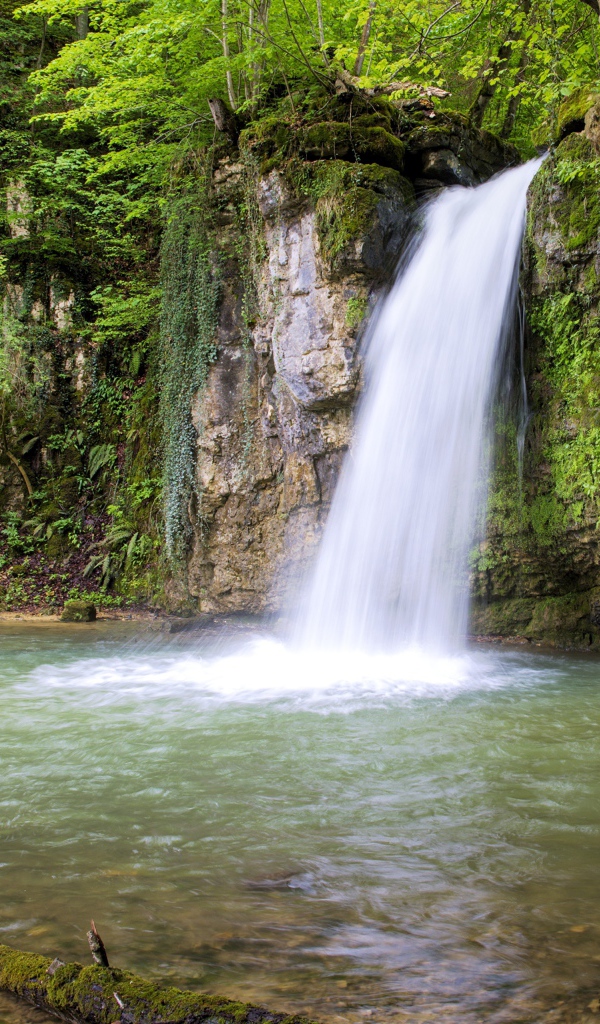 Водопад стекает с крутой горы в озеро 