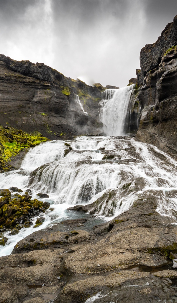 Быстрый горный водопад под серым небом