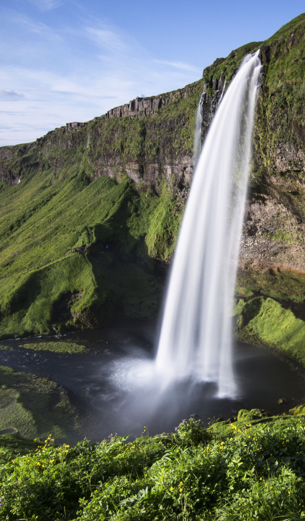 Быстрый водопад Сельяландсфосс стекает со скалы, Исландия