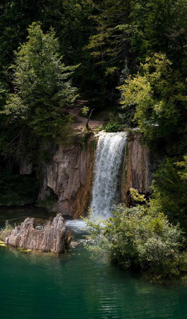 Водопад стекает со скалы в холодное озеро 