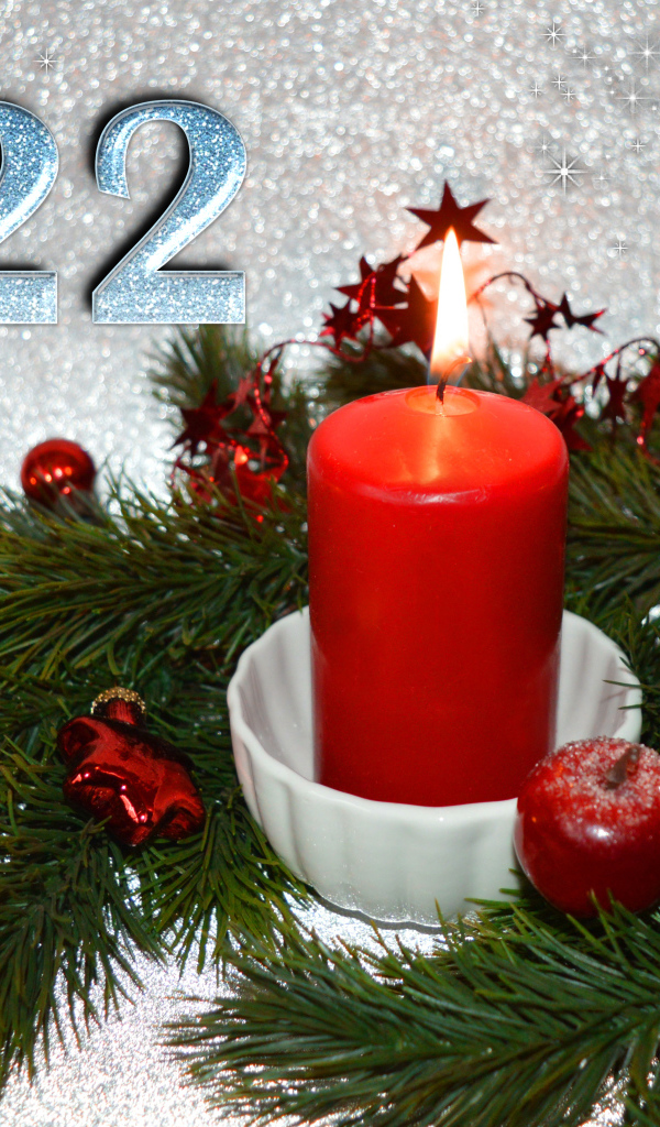 Свеча и еловая ветка с украшениями на новый год 2022