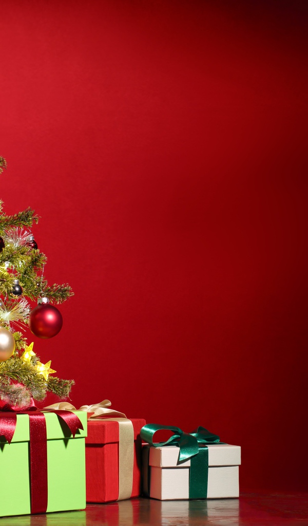 Наряженная ель с подарками на красном фоне на новый год 2022