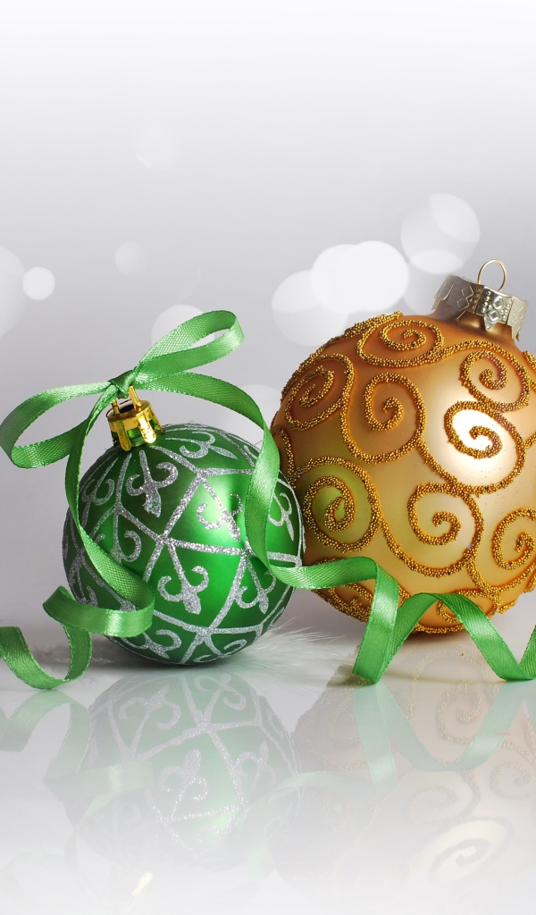 Два красивых елочных шарика с ленточкой на сером фоне 