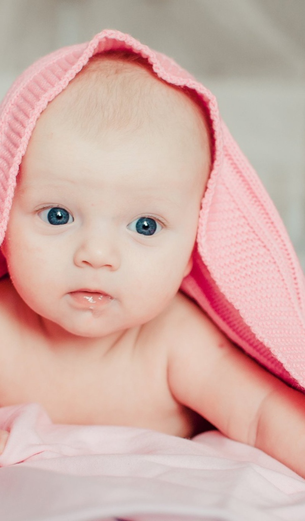 Грудной ребенок лежит под розовым пледом