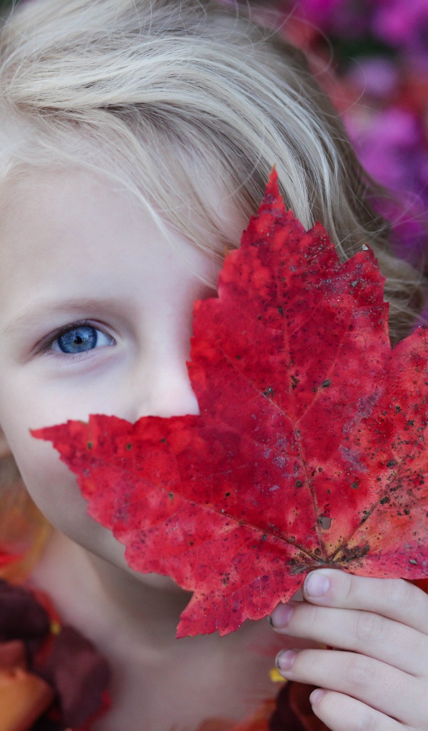 Маленькая девочка закрывает лицо листом