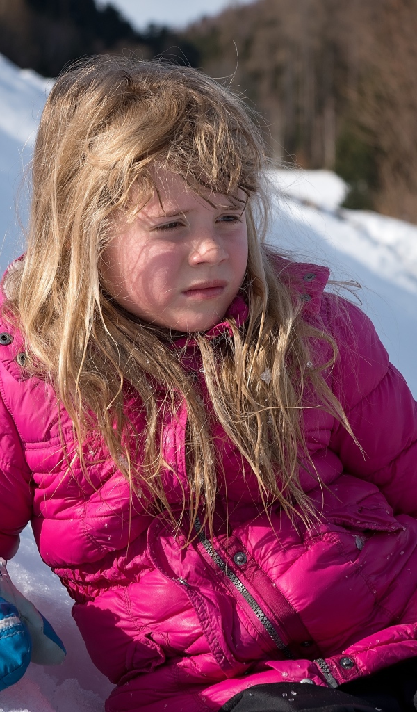 Маленькая девочка лежит на заснеженной горке 