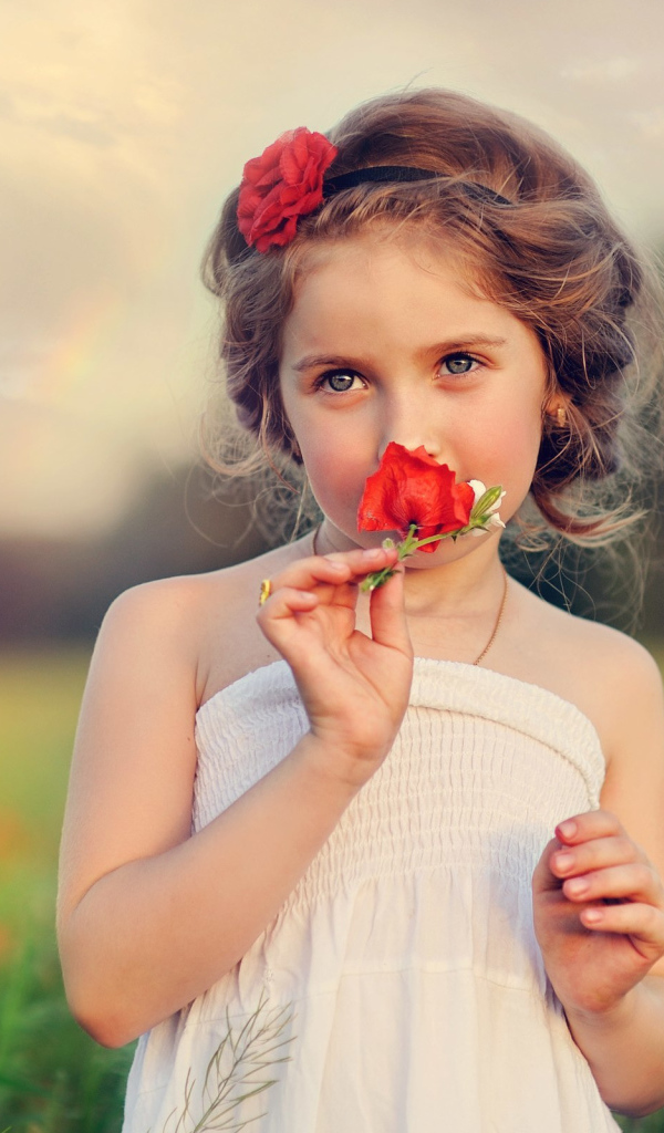 Красивая девочка в белом платье с цветком красного мака в руке 