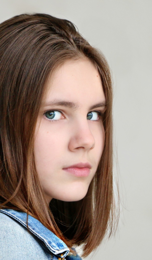 Красивая зеленоглазая девочка на сером фоне