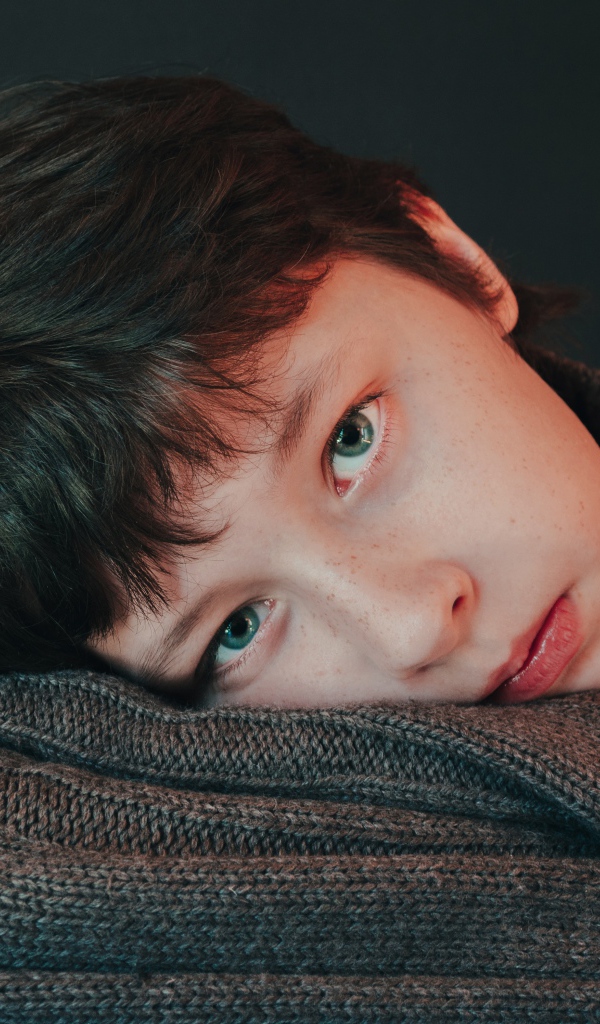 Мальчик в теплом свитере на сером фоне 