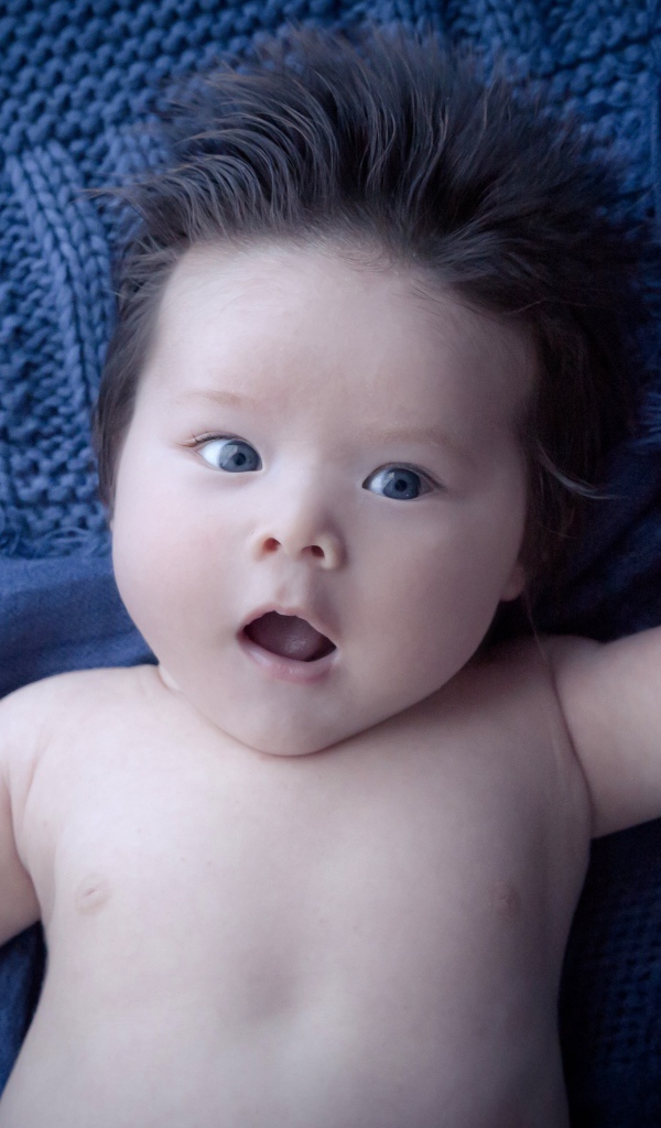 Мальчик с густыми волосами на синем покрывале 