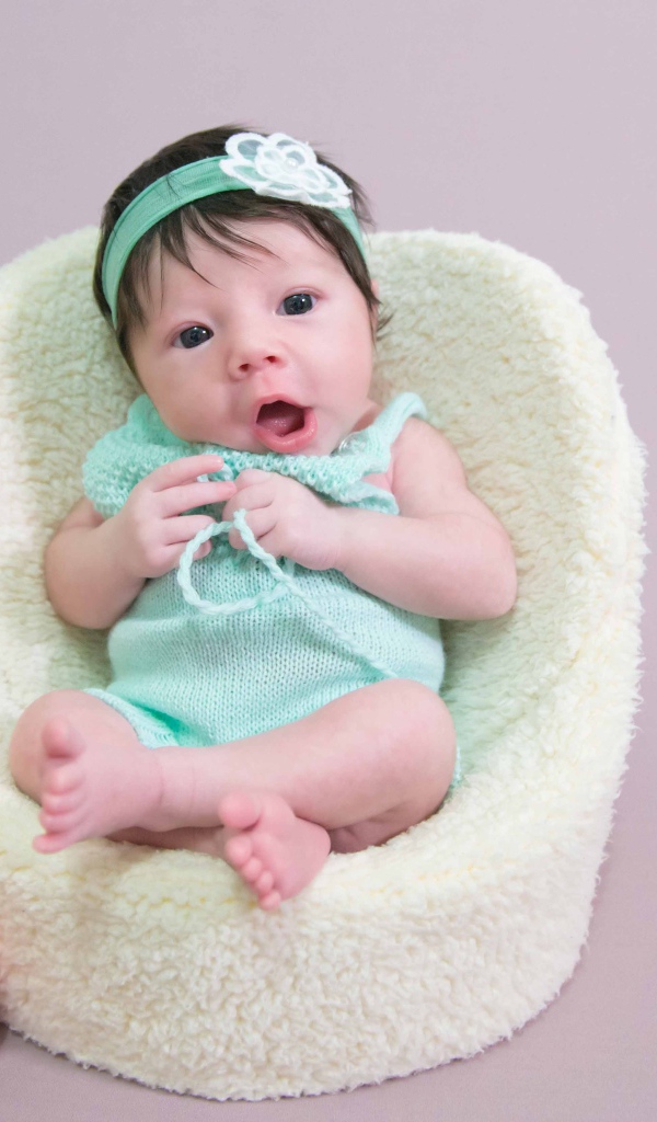 Милая малышка в кресле с букетом цветов