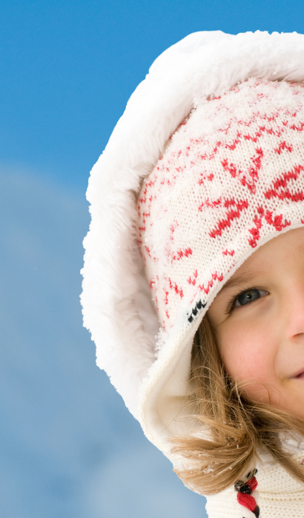 Милая маленькая девочка в шапке на фоне неба