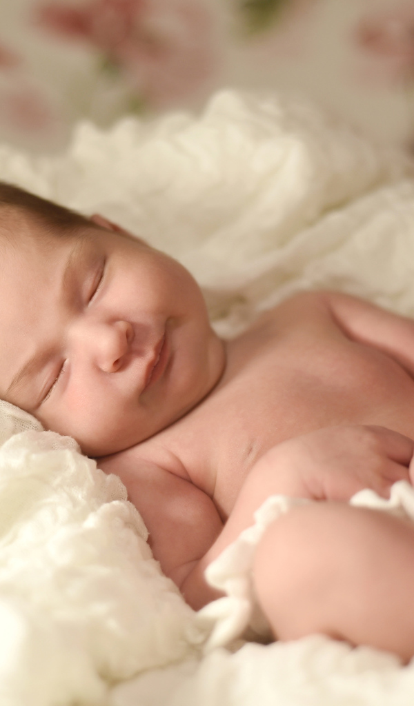 Милый грудной ребенок спит на белом покрывале 