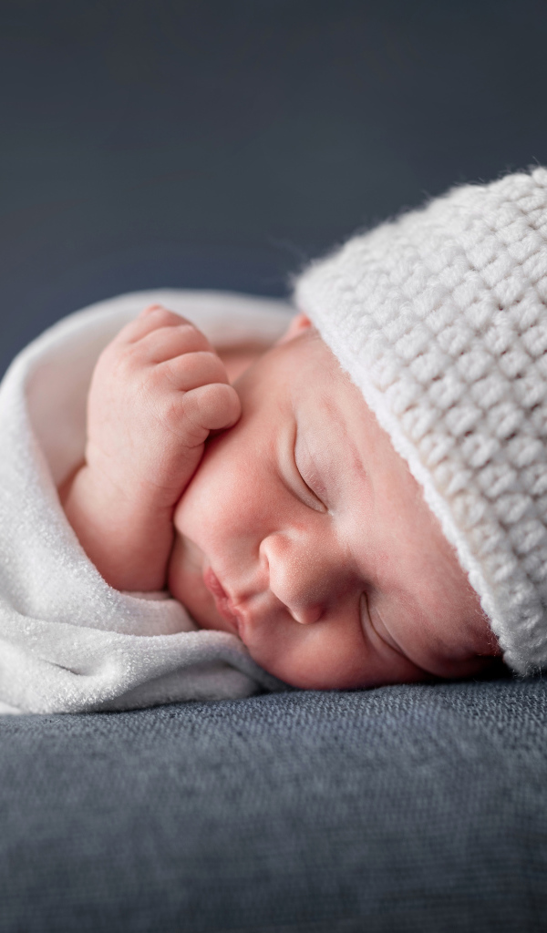 Милый спящий ребенок в белой шапке с ушками