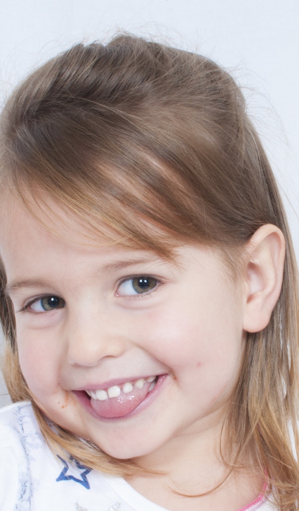 Милая улыбающаяся девочка с высунутым языком