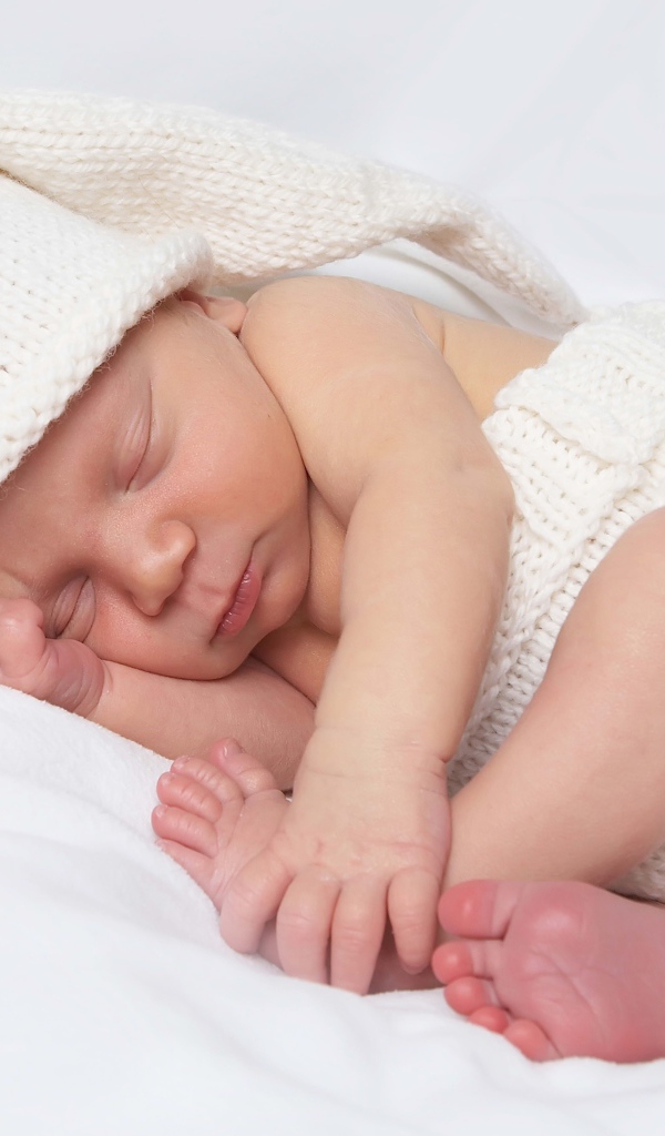 Нежный новорожденный ребенок в белом костюме