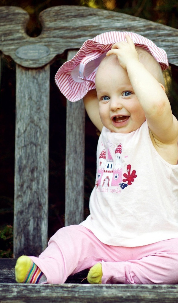 Смешной маленький ребенок сидит на лавке