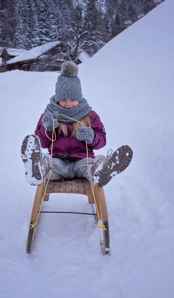 Девочка едет на санках с горки