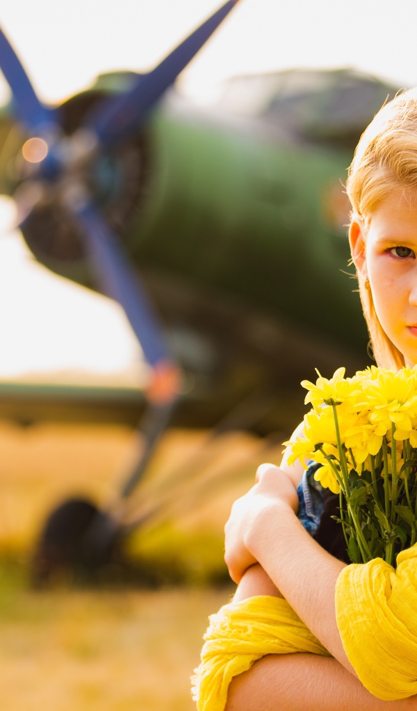 Девочка с букетом желтых хризантем у самолета 