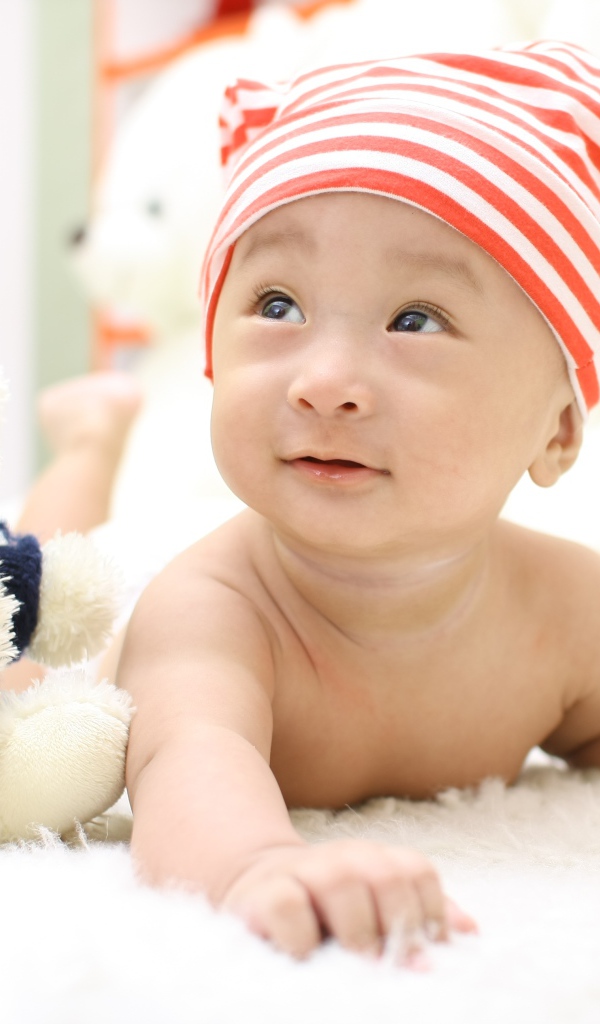 Маленький мальчик азиат на кровати с игрушкой