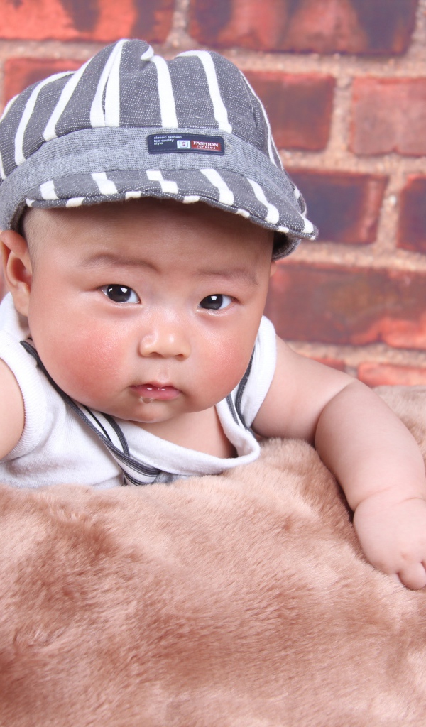 Маленький азиатский ребенок на фоне стены